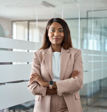 Professional Black woman wearing neutral suit, smiling and standing confidently in modern office setting Professional Black woman wearing neutral suit, smiling and standing confidently in modern office setting